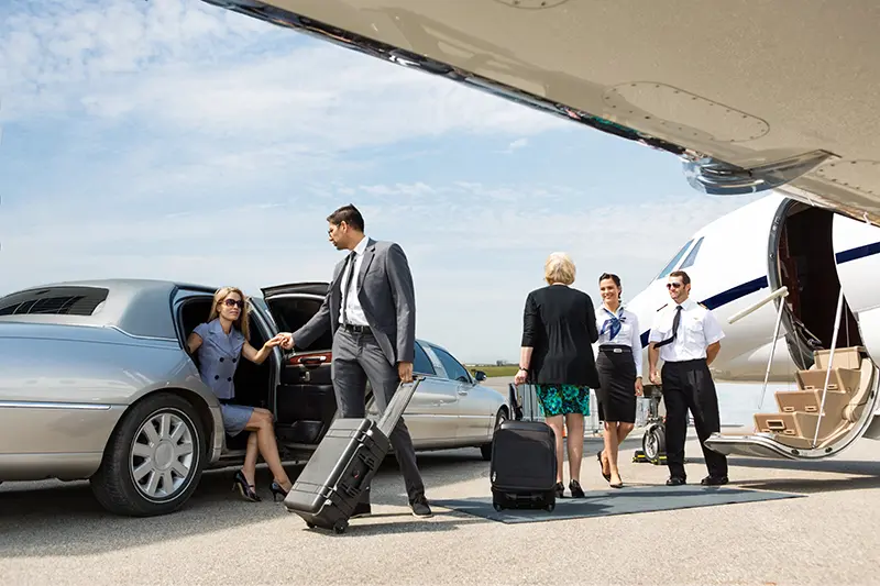People getting off a limousine next to a private jet